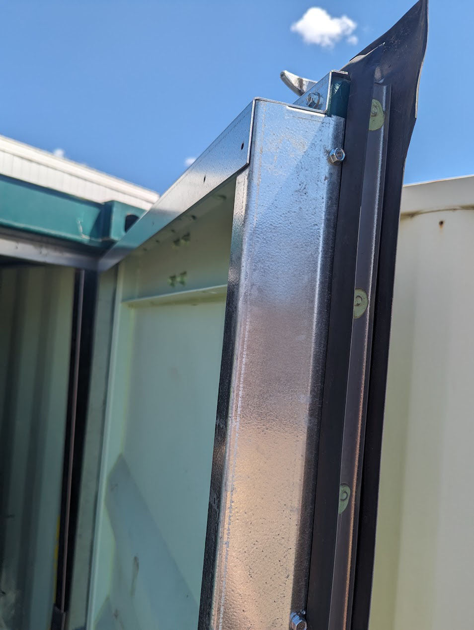 Angled view of galvanized steel container door flashing installed at the top corner, highlighting snug fit and professional finish with fastened hardware